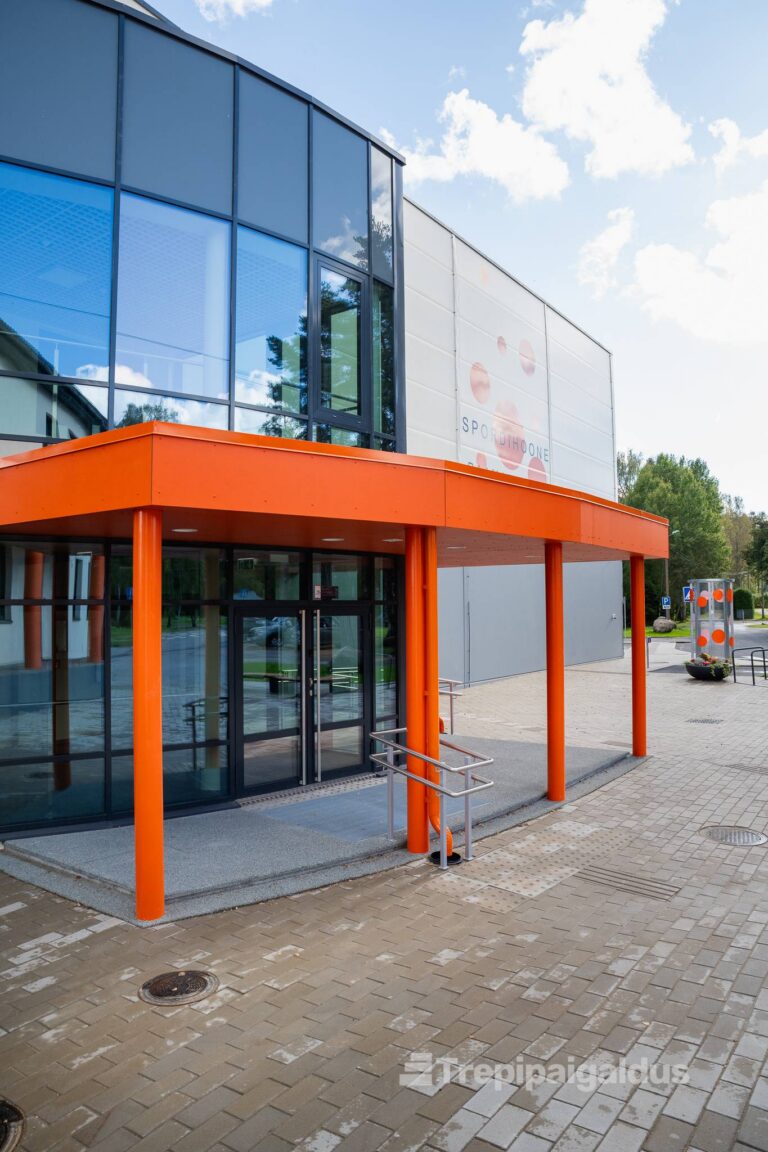 Kaasaegne klaasfassaadiga hoone sissepääs pesubetoonist astmete, kaldtee ja käsipuudega