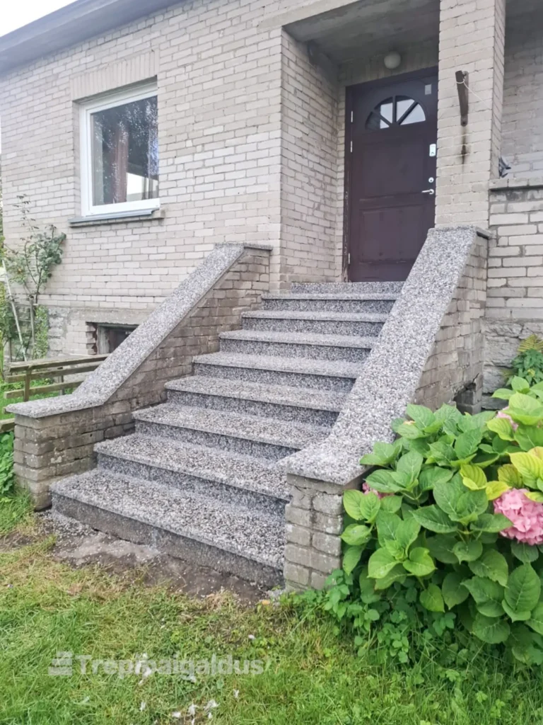 Hallide pesubetoonplaatidega kaetud välistrepp telliskivimaja sissepääsu juures.