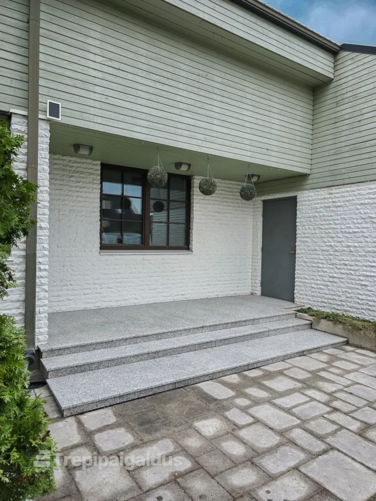 Välistrepi uuendamine Bianco Sardo graniitplaatidega modernse maja sissepääsu juures.