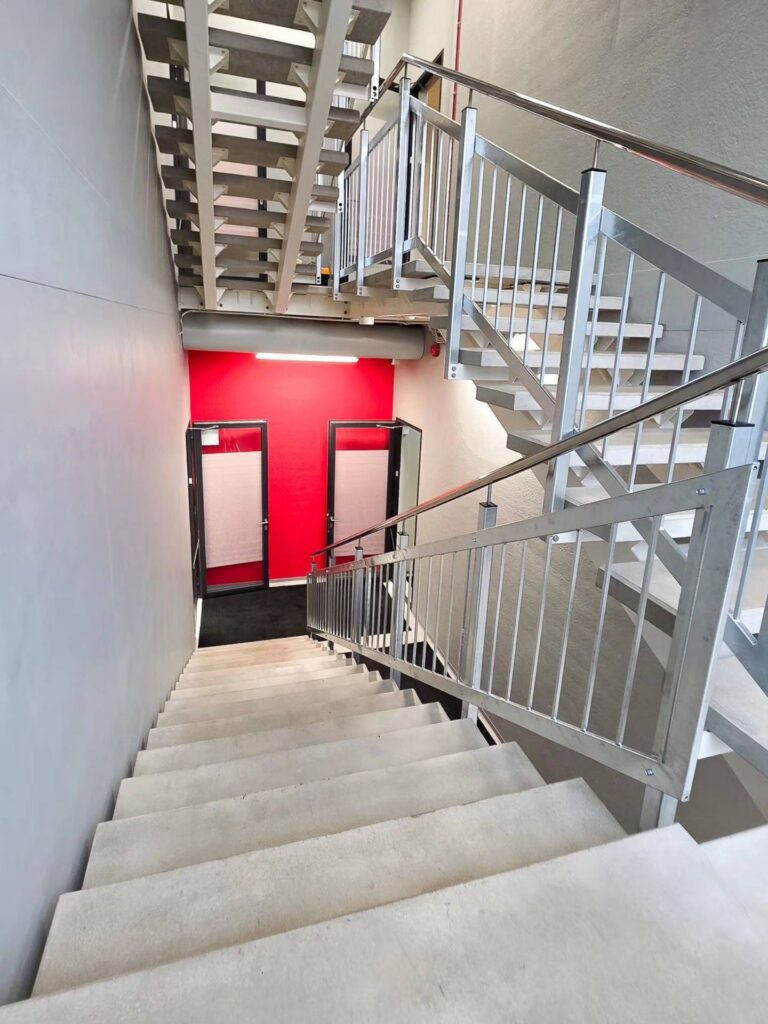 Kontorihoone sisetreppon kaetud hallide silebetoonist plaatidega.