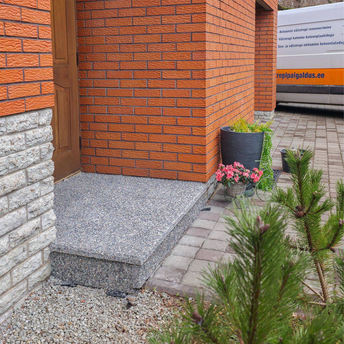 Pesubetoonplaatidega viimistletud välistrepi aste eramaja sissepääsu juures