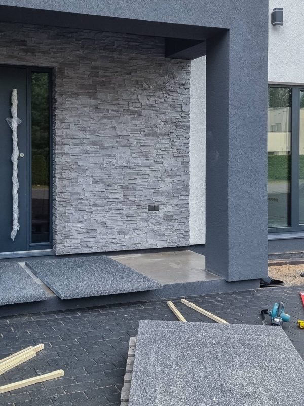 Tumedate pesubetoonist trepiplaatide paigaldus uue kaasaegse eramaja ees.