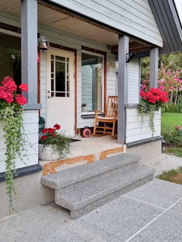 Heleda fassaadiga eramule on ehitatud kahe pesubetoonist astme ja betoontaladega välistrepp. Verandapiirdel on kenad punast värvi lilled.